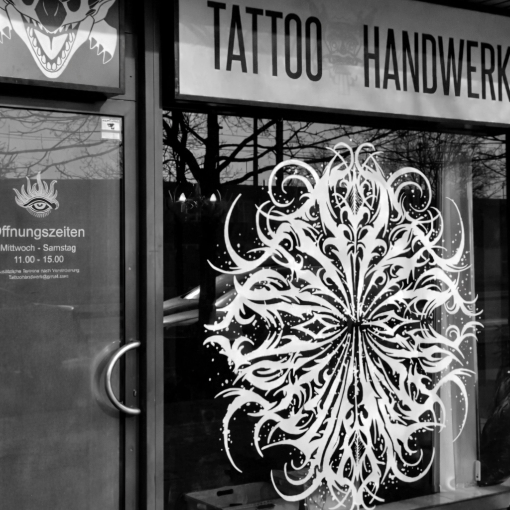 Tattoo Studio mit großem weißen Mandala auf der Fensterfront und schwarz weißer Optik